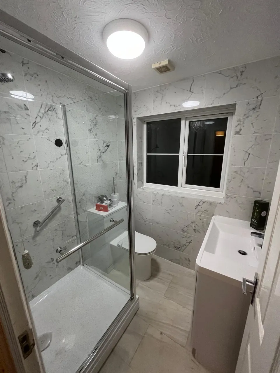 Finished shower room with marble-effect tiles, glass enclosure and vanity unit