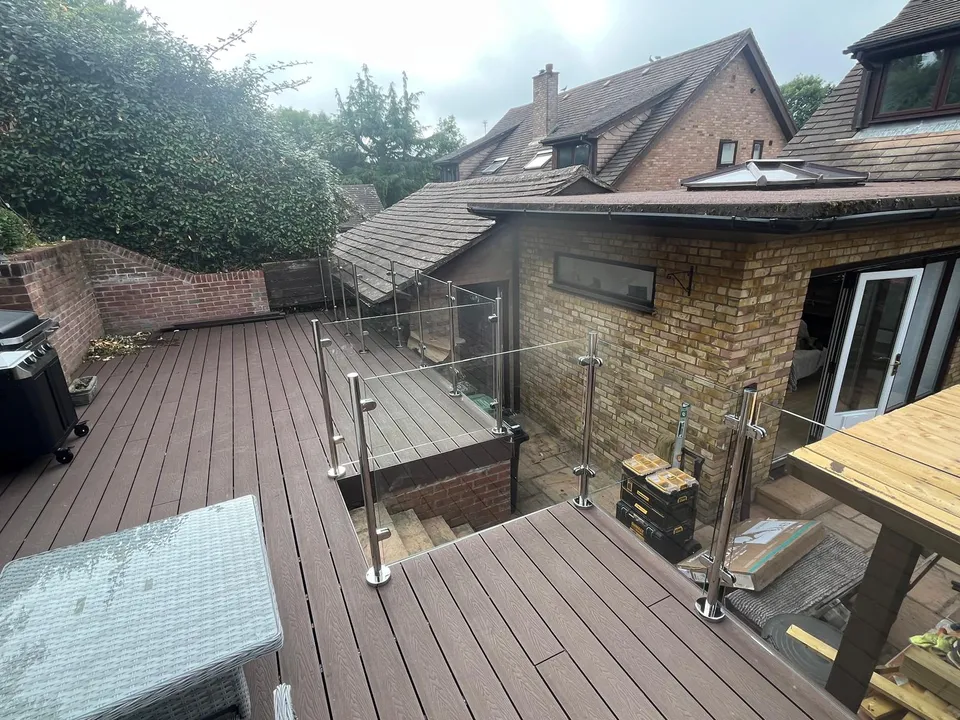 Raised composite deck with glass balustrade and steps down to the garden