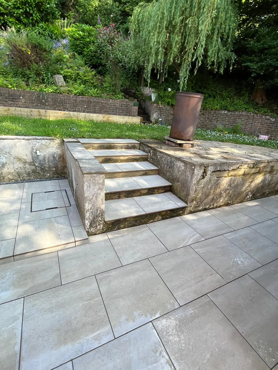 Grey porcelain paving at the foot of stone garden steps