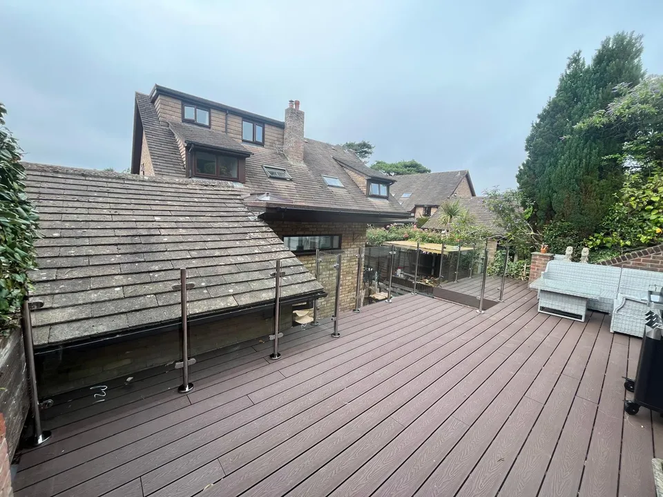 Composite deck with glass balustrade on a raised terrace beside the house