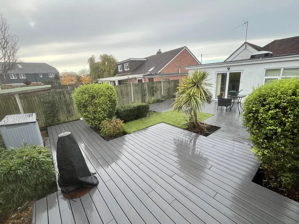 Grey composite decking with planted borders and a palm