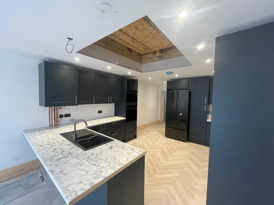 Marble-effect peninsula with black sink and dark tall units