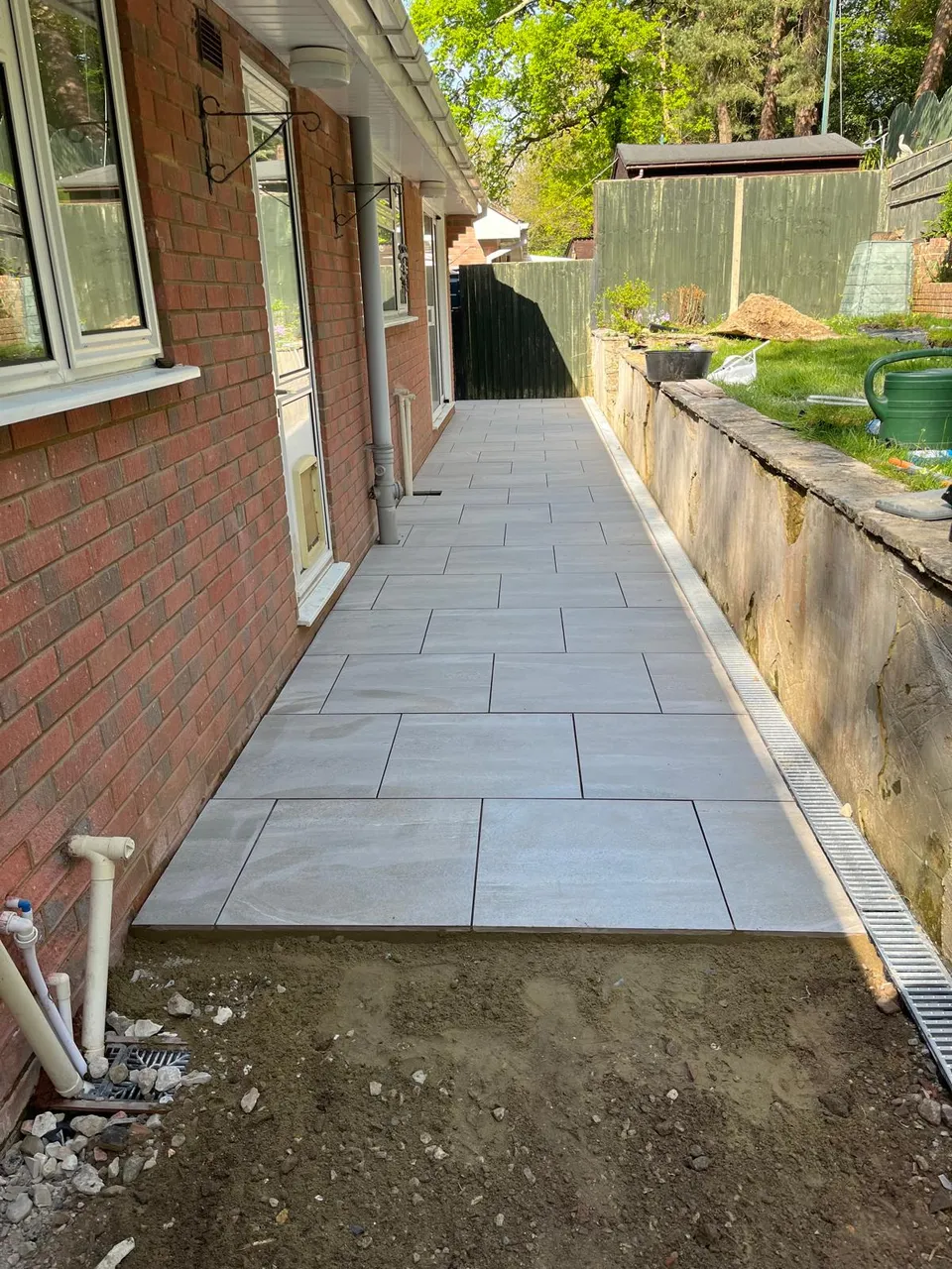 New porcelain paving being laid along the side of the house