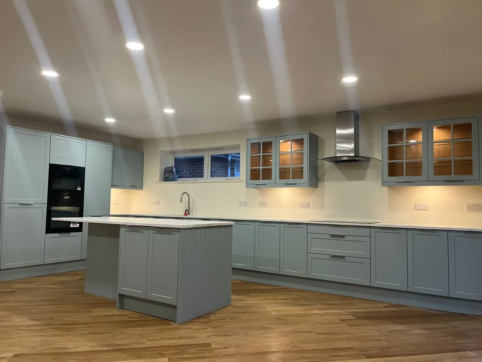 Kitchen island and sage-green wall units with glass-fronted cabinets